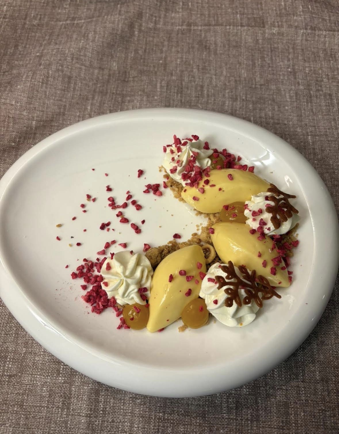 Dessert con quenelle di crema e lamponi disidratati
